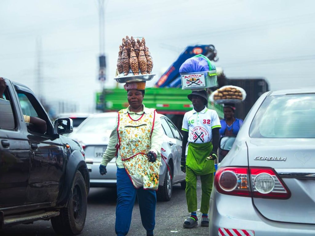 Street vendors selling snacks and goods to drivers in heavy traffic in Accra, Ghana.