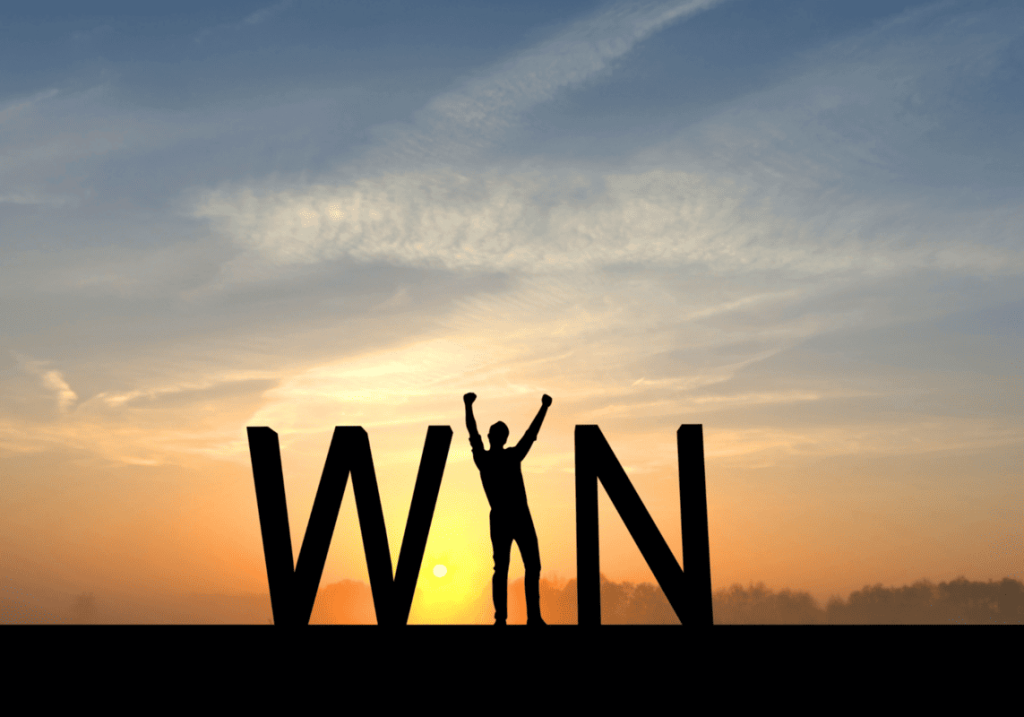 Silhouette of a person raising their arms in victory, standing between large letters spelling "WIN" against a sunrise background.
